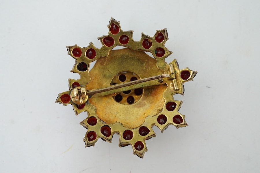 A Victorian style yellow metal and garnet cluster set snow flake brooch, 41mm. Condition - fair